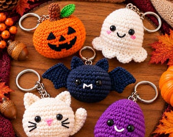 May include: Five crochet keychains featuring a pumpkin, a white ghost, a dark blue bat, a white cat, and a purple creature. Each has a metal ring and black bead eyes. A wooden sign above reads Crochet by Corner Store with a heart icon.