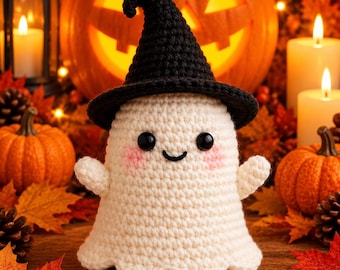 May include: A cream-colored crocheted ghost figurine wearing a black pointed witch hat. The ghost has two small black bead eyes, a stitched black smile, and pink blush marks on its cheeks. The figure has a scalloped bottom edge.