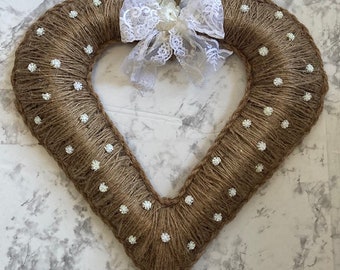 May include: A heart-shaped wreath made of burlap with white polka dots and a white lace bow.