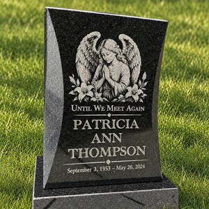 Może przedstawiać: Czarny nagrobek z granitu o polerowanym wykończeniu, z wygrawerowanym aniołem ze skrzydłami i liliami. Tekst głosi: UNTIL WE MEET AGAIN, PATRICIA ANN THOMPSON, September 3, 1953 - May 26, 2024. Pomnik umieszczony jest na prostokątnej podstawie.