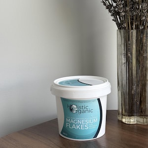 May include: A white plastic tub of Holistic Organic Magnesium Flakes with a light blue and dark blue label. The label features the text Holistic Organic, Magnesium Flakes, 100% Pure Organically Sourced, Pure Magnesium Chloride, and 800 g.