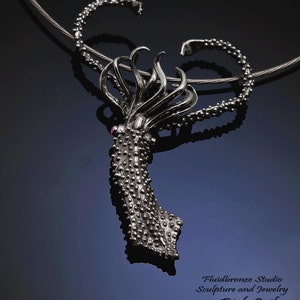 May include: A silver pendant shaped like a giant squid with a pink gem for an eye. The pendant is hanging from a silver chain.