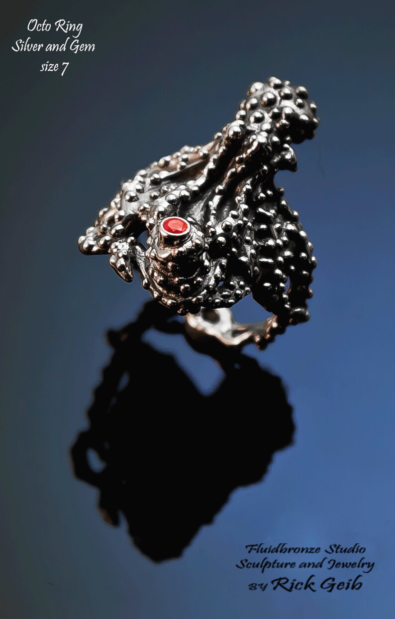 May include: A silver ring with a textured octopus design and a red gemstone. The ring is size 7. "Octo Ring Silver and Gem size 7" is written above the ring.