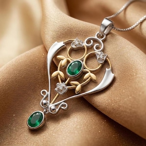 May include: A silver and gold pendant necklace featuring an oval-cut green gemstone at the center and a smaller oval green gemstone at the base. The metal frame displays intricate scrollwork, leaf motifs, and small inset clear stones.