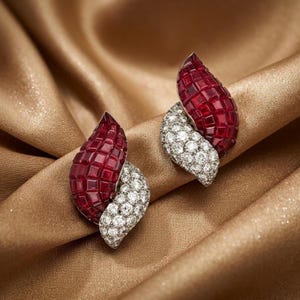 May include: A pair of earrings featuring a leaf-shaped design. Each earring is composed of a cluster of square-cut deep red rubies and a section of round brilliant-cut white diamonds set in a metallic frame with a curved, layered structure.