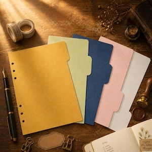 May include: A set of five tabbed planner dividers in mustard yellow, sage green, navy blue, soft pink, and light gray. Each divider features a vertical row of six circular punched holes along the left edge for binding in a ring-bound planner system.