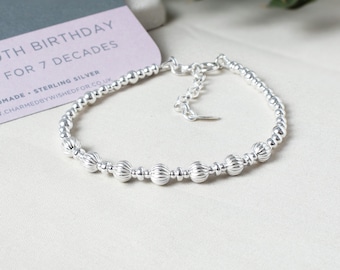 May include: A silver beaded bracelet with a clasp closure. The beads are round and have a textured surface. The bracelet is made of sterling silver and is 7 inches long.