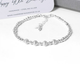 May include: A silver beaded bracelet with a charm. The bracelet has a clasp and is made of sterling silver. The charm is a small, silver heart. The bracelet is on a white background. The text on the card reads "Happy 40th Birthday! Handmade - Sterling Silver www.charmedbywishedfor.co.uk"