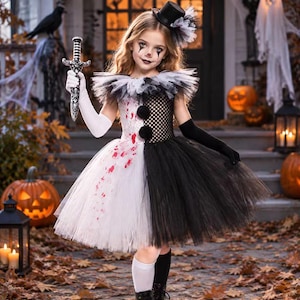 May include: A split-color dress featuring a white side with red blood-like splatters and a black side with a mesh bodice. The dress includes a ruffled collar, two black pom-poms, a mini top hat with tulle, and one long white glove.