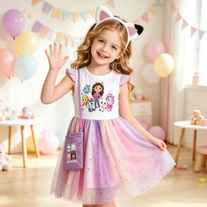 May include: A white sleeveless dress with ruffled shoulders and a graphic print of Gabby and her cat friends. The skirt features layers of pastel rainbow tulle with silver star accents. A matching purple crossbody bag and cat ear headband.