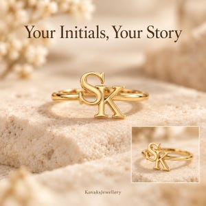 Puede incluir: Un anillo de tono dorado con las letras S y K como punto focal. El texto Your Initials, Your Story aparece en la parte superior y el texto KavaksJewellery en la parte inferior. El anillo se muestra en dos vistas sobre una superficie texturizada.
