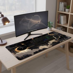 May include: A rectangular desk mat featuring a celestial design with a large golden crescent moon, scattered stars, and dark clouds against a black background. The mat is positioned on a wooden desk surface beneath a computer monitor and keyboard.