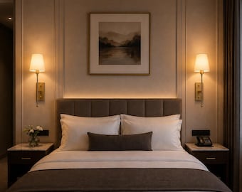 May include: A bedroom featuring a bed with white linens, a dark brown runner, and a matching rectangular throw pillow. Two dark wood nightstands with marble tops flank the bed, each with a gold wall sconce and a framed landscape painting above.