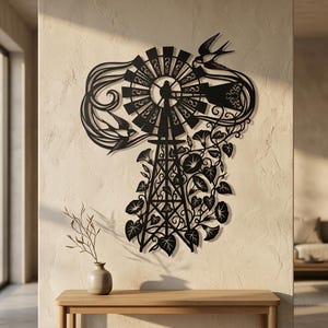 Puede incluir: Una pieza de arte mural de metal negro con la silueta de un molino de viento y patrones recortados. El diseño incluye dos golondrinas en vuelo y enredaderas de campanillas con hojas y flores que envuelven la base de la torre del molino.