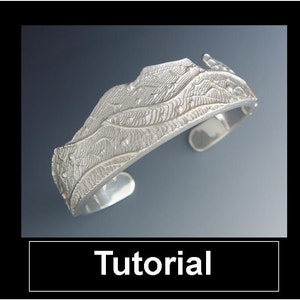 May include: A silver cuff bracelet with an intricate, textured design. The bracelet features a detailed pattern of lines and shapes, with a slightly curved shape. The word "Tutorial" is displayed in a white box at the bottom.