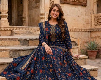 Könnte beinhalten: Ein marineblaues Langarmkleid mit einem sich wiederholenden Blumenmuster in Rot-, Orange- und Grüntönen. Das Kleid hat einen Rundhalsausschnitt mit einem zentralen vertikalen Stickereieinsatz und einen passenden Schal über einer Schulter.