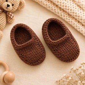 Puede incluir: Un par de patucos de ganchillo de color marrón oscuro con un diseño sencillo sin cordones, puntera redondeada y una construcción de punto grueso y texturizado. Los patucos están hechos de hilo y tienen un color sólido y profundo.