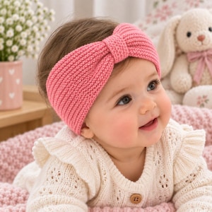 May include: A pink knit headband featuring a central knotted bow detail. The accessory is crafted with a ribbed texture and a soft, flexible construction, designed to fit comfortably around the head with a secure and snug fit.