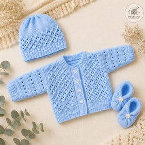 Può includere: Un set lavorato a maglia color azzurro per neonati composto da un berretto, un cardigan a maniche lunghe con quattro bottoni bianchi e un paio di scarpine abbinate con piccoli fiori bianchi. Gli articoli presentano un motivo a rombi traforato.