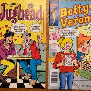 May include: Two vintage Archie Comics comic books. One features Jughead and the other Betty and Veronica. The Jughead comic shows Jughead and Veronica at a table. The Betty and Veronica comic shows Betty giving Archie a birthday card.