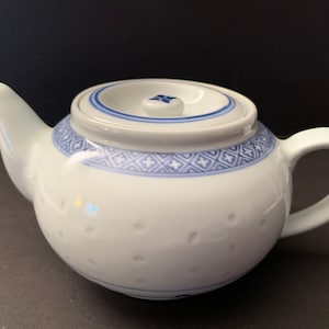 May include: A white teapot with a blue and white floral design. The teapot has a lid and a handle.