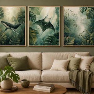 Könnte beinhalten: Ein Set aus drei gerahmten Wandbildern mit Unterwasserszenen, die einen Wal, einen Mantarochen und einen Fischschwarm zeigen, umgeben von großen grünen Tropenblättern. Die Kunstwerke verwenden eine Palette aus tiefen Grüntönen und hellem Licht.