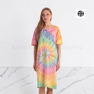 May include: A knee-length dress featuring a vibrant tie-dye pattern with swirling colors of pink, yellow, orange, green, and blue. The garment has short sleeves and a round neckline. The logo AH is visible in the top right corner of the image.