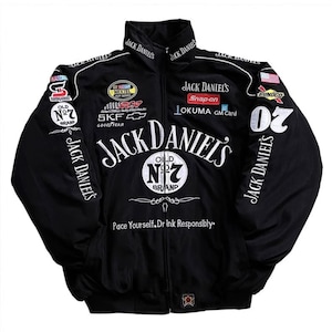 Könnte beinhalten: Eine schwarze Racing-Jacke mit Reißverschluss, weißem Jack Daniel's-Schriftzug, Old No. 7-Logos und verschiedenen gestickten Sponsoren-Aufnähern wie NASCAR, Snap-on und Goodyear. Der Text Pace Yourself. Drink Responsibly steht auf der Vorderseite.