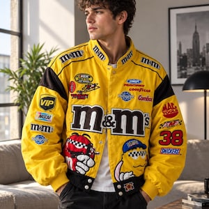 Könnte beinhalten: Eine leuchtend gelbe Bomberjacke im Rennsport-Stil mit zahlreichen gestickten Markenlogos wie M&M's, NASCAR, Snickers und Pedigree. Die Jacke hat schwarze Akzente an den Ärmeln und am Saum, einen Druckknopfverschluss und große grafische Aufnäher von M&M-Charakteren auf den Vorderteilen.
