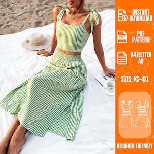 May include: A two-piece set consisting of a light green and white gingham crop top with tie-shoulder straps and a matching high-waisted midi skirt with a side slit. The set is displayed alongside a straw hat and a white coffee mug.