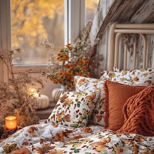 Peut inclure: Une parure de lit à motif de feuilles et de baies d'automne sur fond blanc, accompagnée de coussins orange brûlé et d'une couverture en tricot épais, disposée sur un cadre de lit près d'une fenêtre avec un feuillage automnal.