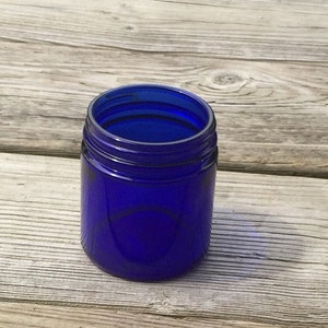 Peut inclure: Un pot en verre bleu cobalt avec une large ouverture. Le pot est vide et posé sur une surface en bois.