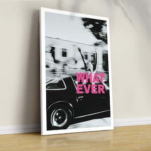 May include: A rectangular wall art print featuring a black and white photograph of a person with arms raised in a car, with the bright pink text "WHAT EVER" overlaid in the centre. The print is framed in a thin white border and stands upright.