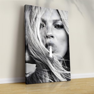 May include: A black and white canvas print featuring a close-up portrait of a person with long, flowing hair partially obscuring their face. The individual is holding a cigarette between their lips, with wisps of smoke visible around the mouth.