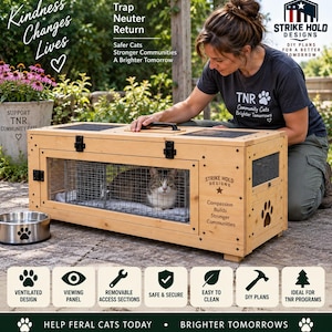 Puede incluir: Una trampa rectangular de madera para gatos con un panel de visualización transparente, interior de malla metálica y asa negra. El lateral muestra el texto Strike Hold Designs, Compassion Builds Stronger Communities y una huella de pata.