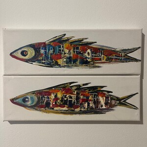 Puede incluir: Dos lienzos rectangulares con pinturas al óleo de peces. Cada pez está realizado con pinceladas gruesas y texturizadas en una paleta de rojo, azul, amarillo y negro sobre un fondo blanco, mostrando un estilo abstracto y superpuesto.