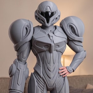 Puede incluir: Un traje de armadura gris de cuerpo completo que presenta un casco redondeado con una visera oscura, grandes hombreras y un cañón cilíndrico en el brazo derecho. El traje muestra paneles intrincados y placas segmentadas en todo el diseño.