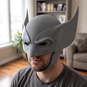 May include: A grey, 3D-printed mask featuring a textured surface, pointed ear-like projections on the sides, and a central nose bridge. The mask covers the upper portion of the face, including the forehead and temples, with cutouts for the eyes.