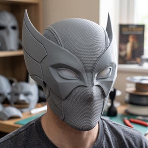 May include: A gray, full-head helmet featuring a textured, honeycomb-like surface pattern and two prominent, upward-curving wing-like protrusions on the sides. The helmet includes almond-shaped eye openings with smooth, white, opaque lenses.