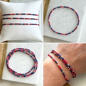 May include: A red, white, and blue beaded bracelet with gold accents. The bracelet is shown on a wrist and laid flat on a white surface.