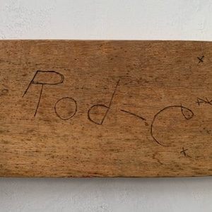May include: A close-up of a wooden sign with the word "Rod" written on it in black marker.