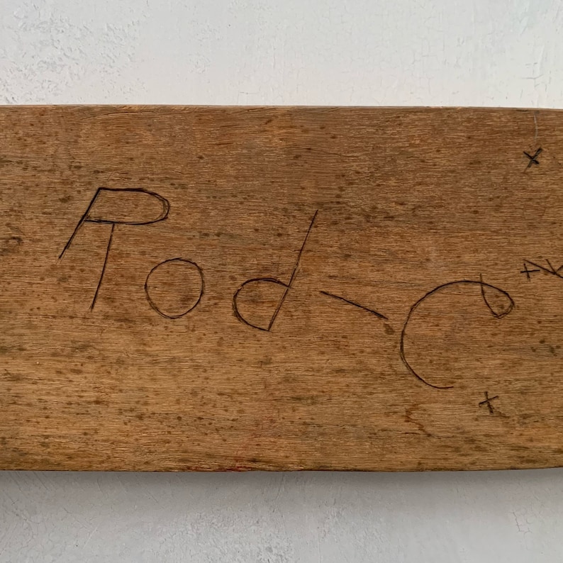 May include: A close-up of a wooden sign with the word "Rod" written on it in black marker.