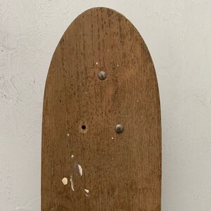 May include: A close-up of a wooden board with a rounded top and two metal fasteners. The board is brown and has a natural wood grain.