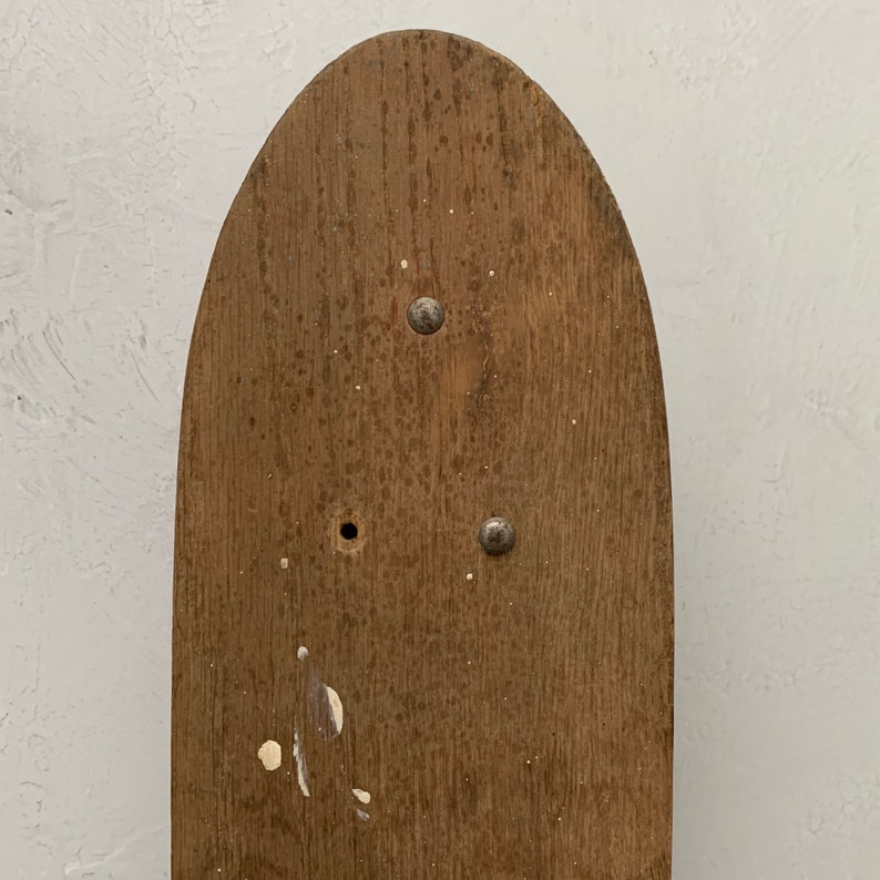 May include: A close-up of a wooden board with a rounded top and two metal fasteners. The board is brown and has a natural wood grain.