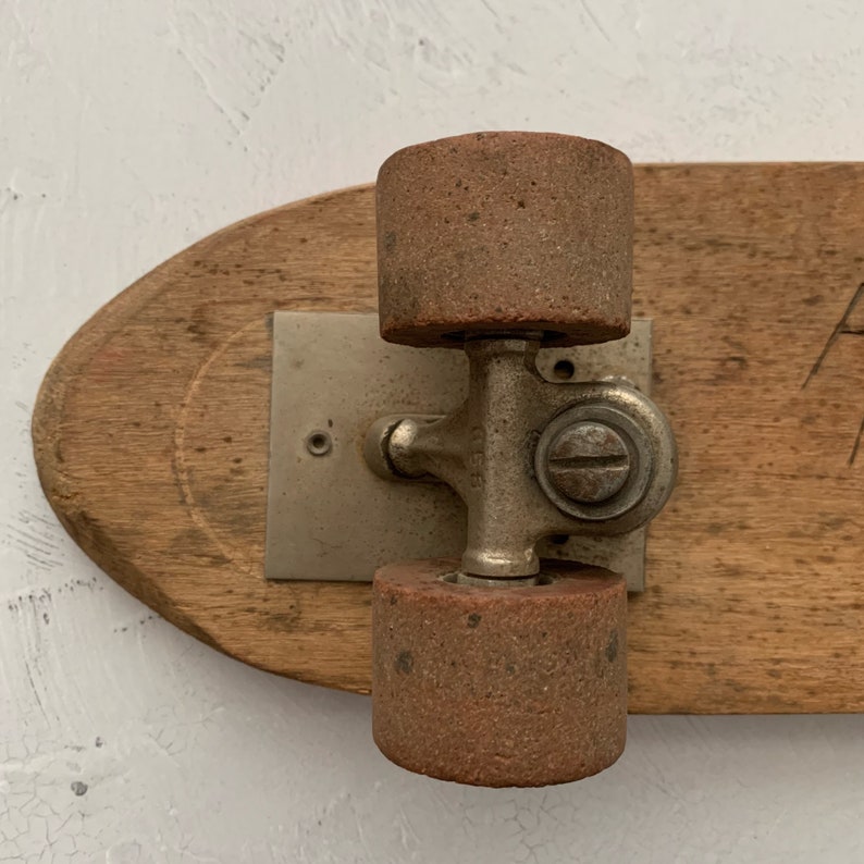 May include: A vintage wooden skateboard with two brown wheels and a silver metal truck. The skateboard is made of wood and has a worn, rustic look.