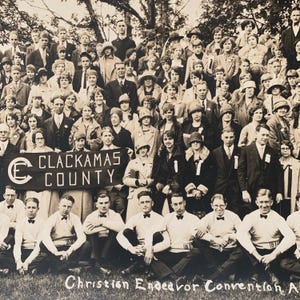 May include: A black and white photograph of a large group of people, mostly women, gathered for a Christian Endeavor Convention in Clackamas County. The group is holding a banner that reads "Clackamas County".