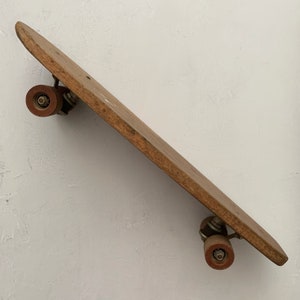 May include: A vintage wooden skateboard with red wheels. The skateboard is in good condition and has a natural wood finish.