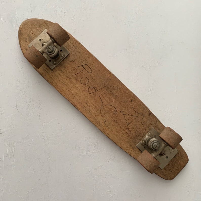 May include: A vintage wooden skateboard with metal wheels and the words "Pod-C" written on the deck.