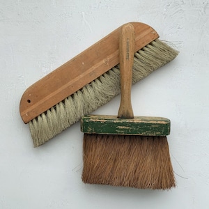 May include: Two vintage wooden brushes. One is a long, rectangular brush with light-colored bristles. The other is a smaller, rectangular brush with a green-painted handle and brown bristles. The text "6 BRUSH-RITE" is visible on the handle.