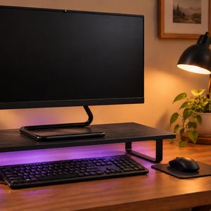 May include: A black wooden monitor stand with a rectangular top and two metal legs, featuring integrated purple LED lighting underneath. The stand supports a computer monitor, with a black keyboard and mouse positioned on the desk surface below.